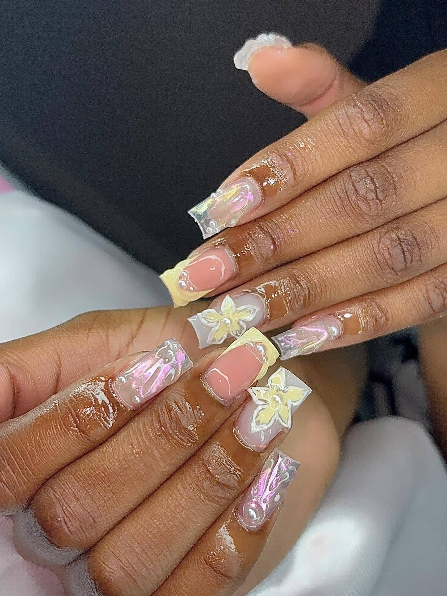 Square set with iridescent aurora nails, butter-yellow French tips, star details and 3D yellow flowers with pearls.