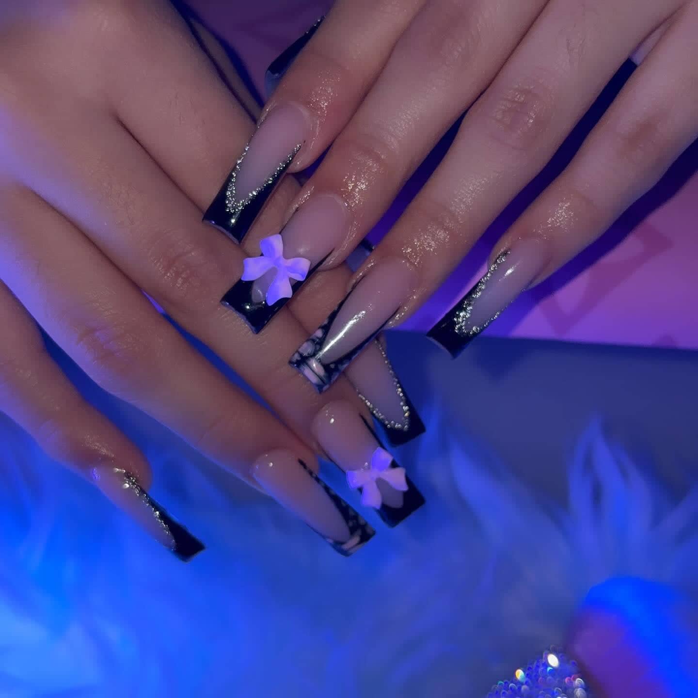 Long square set with black French tips outlined in silver glitter and lilac 3D bow charms.