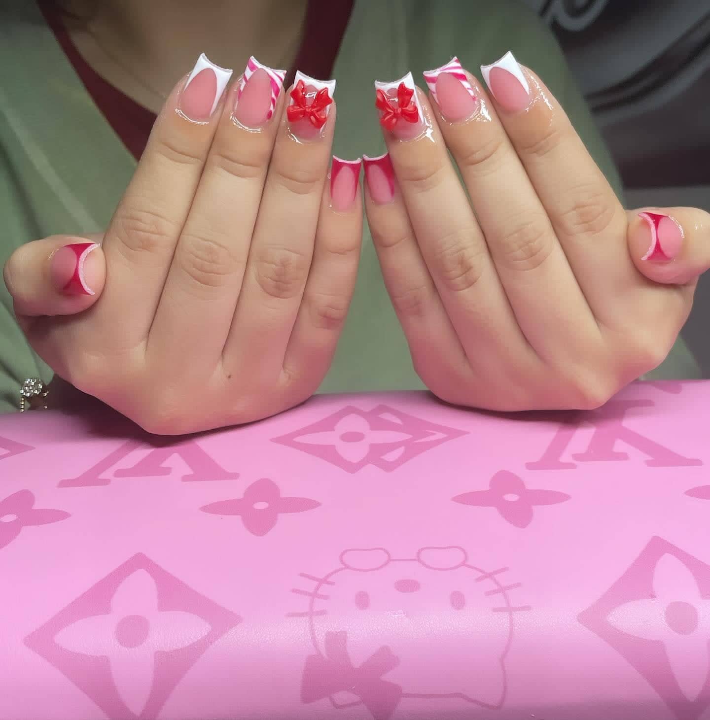 Short square set with white and pink French tips, candy-cane stripes and red 3D bows.