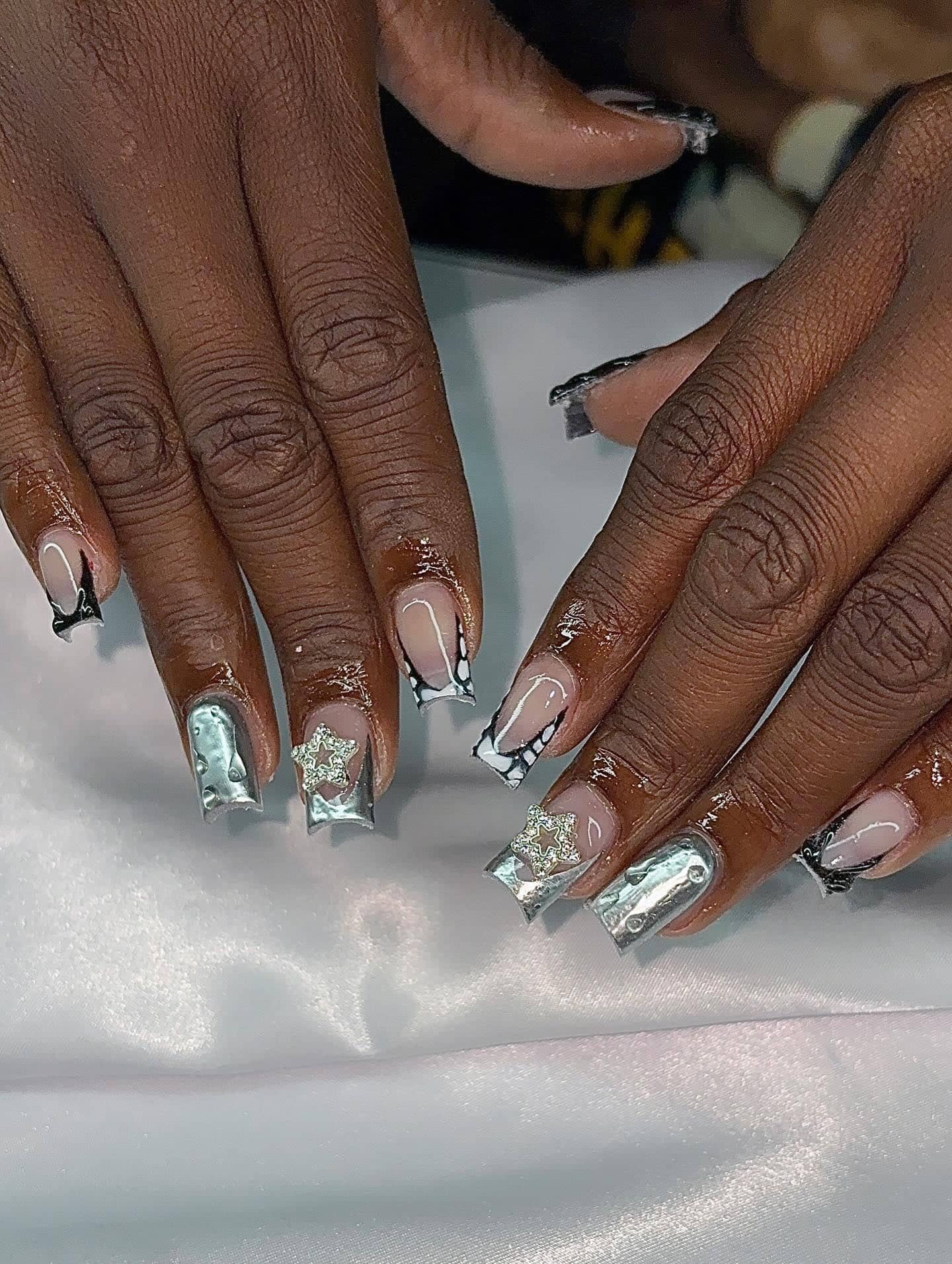 Square set with molten silver chrome nails, black-outlined French tips and rhinestone star charms.