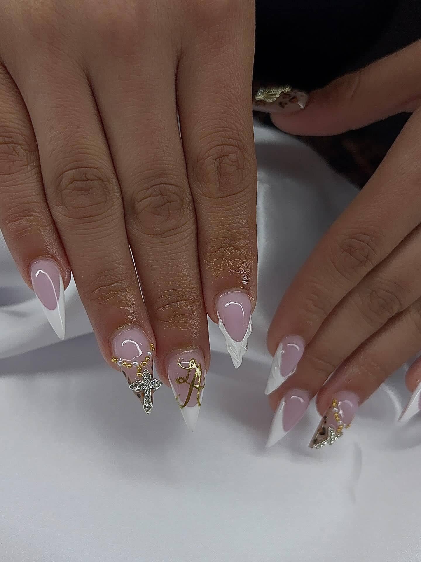 Stiletto set with white French tips, a gold initial charm, a cross charm and a pearl chain.