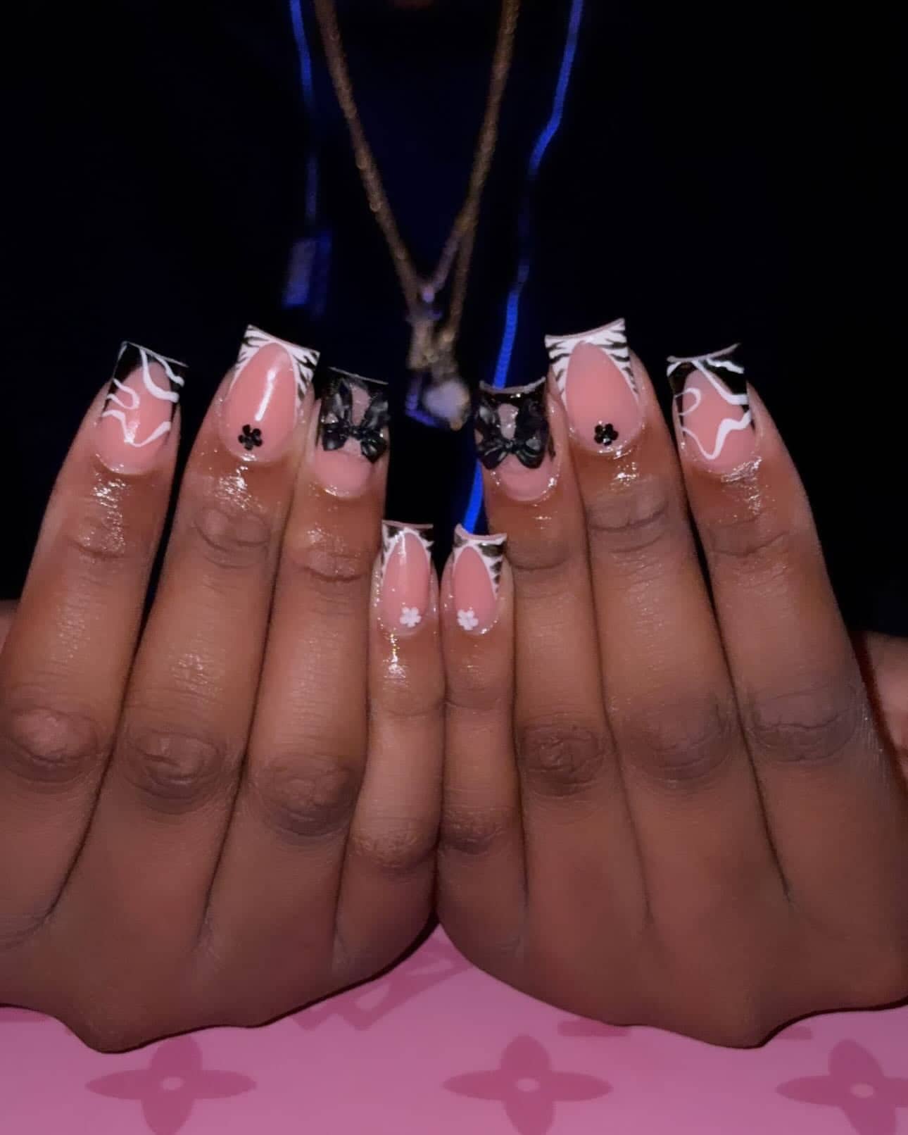 Square set with black French tips, white zebra lines, black bow charms and tiny painted flowers.