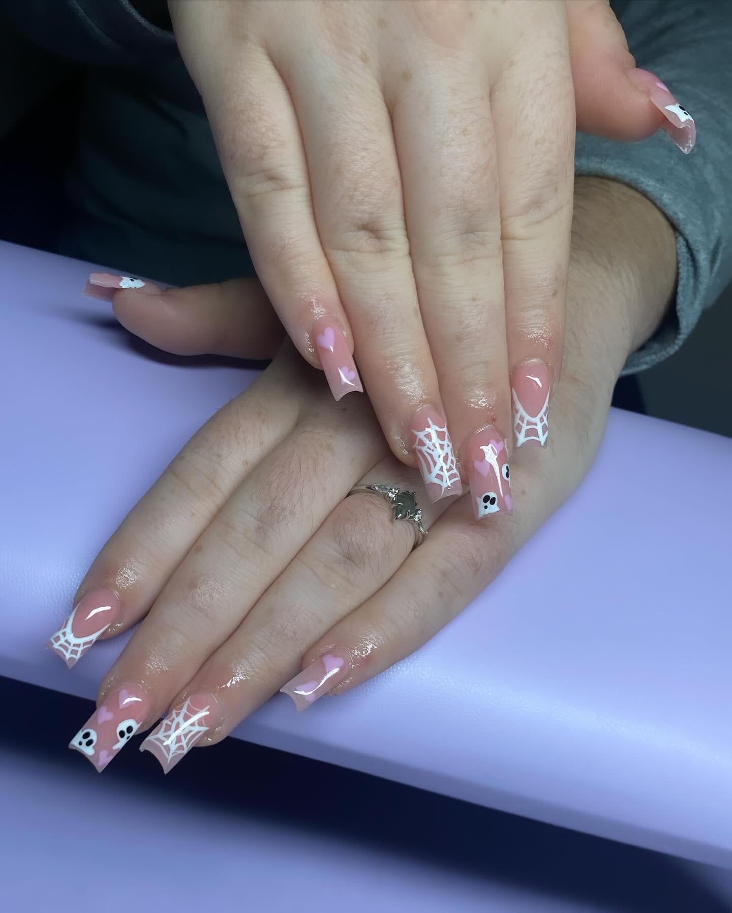 Halloween set with soft pink nails, white hand-painted spiderwebs and tiny ghost faces.