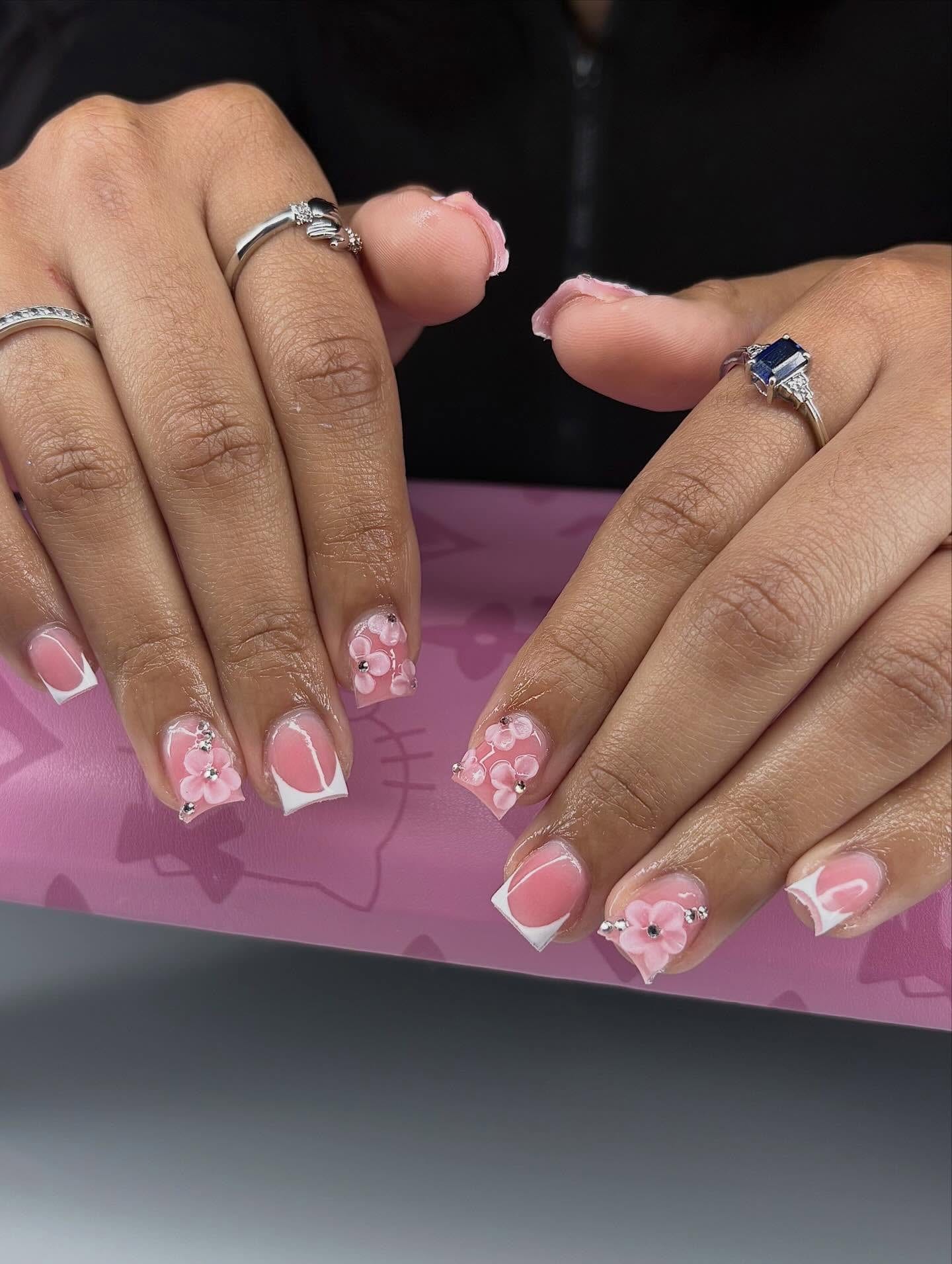 Short square set with crisp white French tips and pink 3D flowers with rhinestone centers.