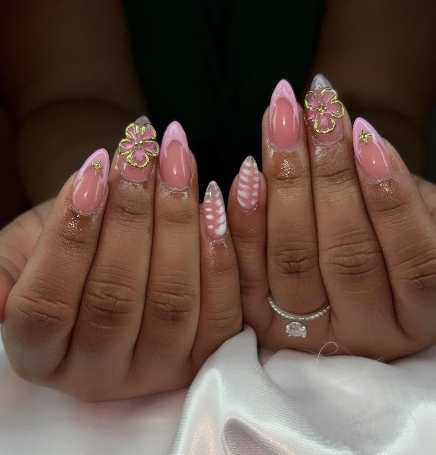 Almond pink French set with gold-outlined 3D flowers, gold star accents and a pink-and-white swirl nail.