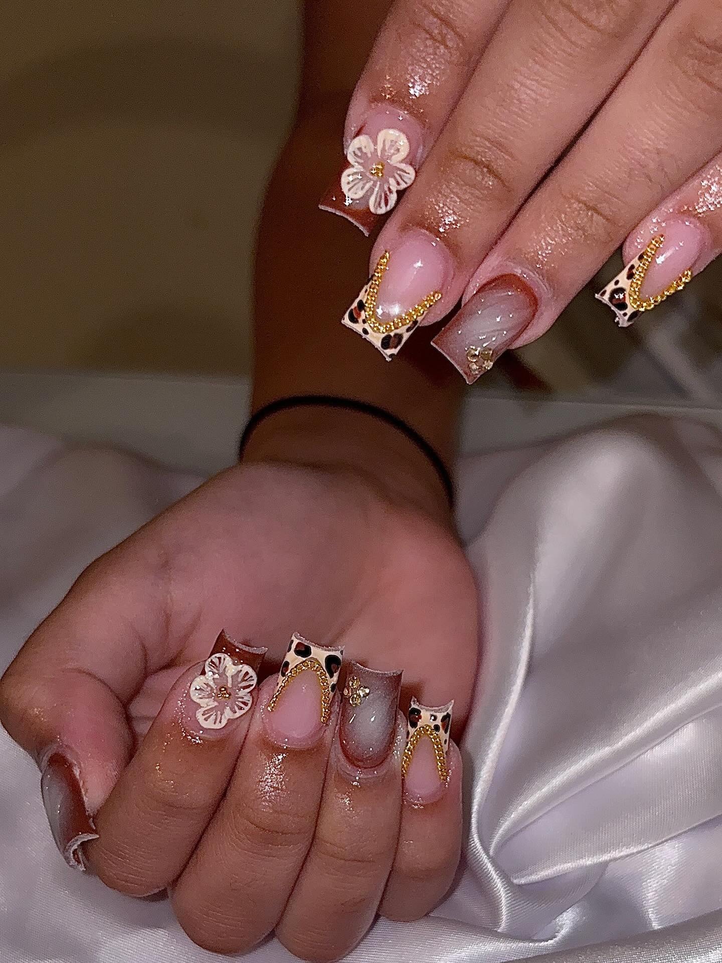 Close-up of a square set with leopard-print tips, gold chain V-details and a white 3D flower.