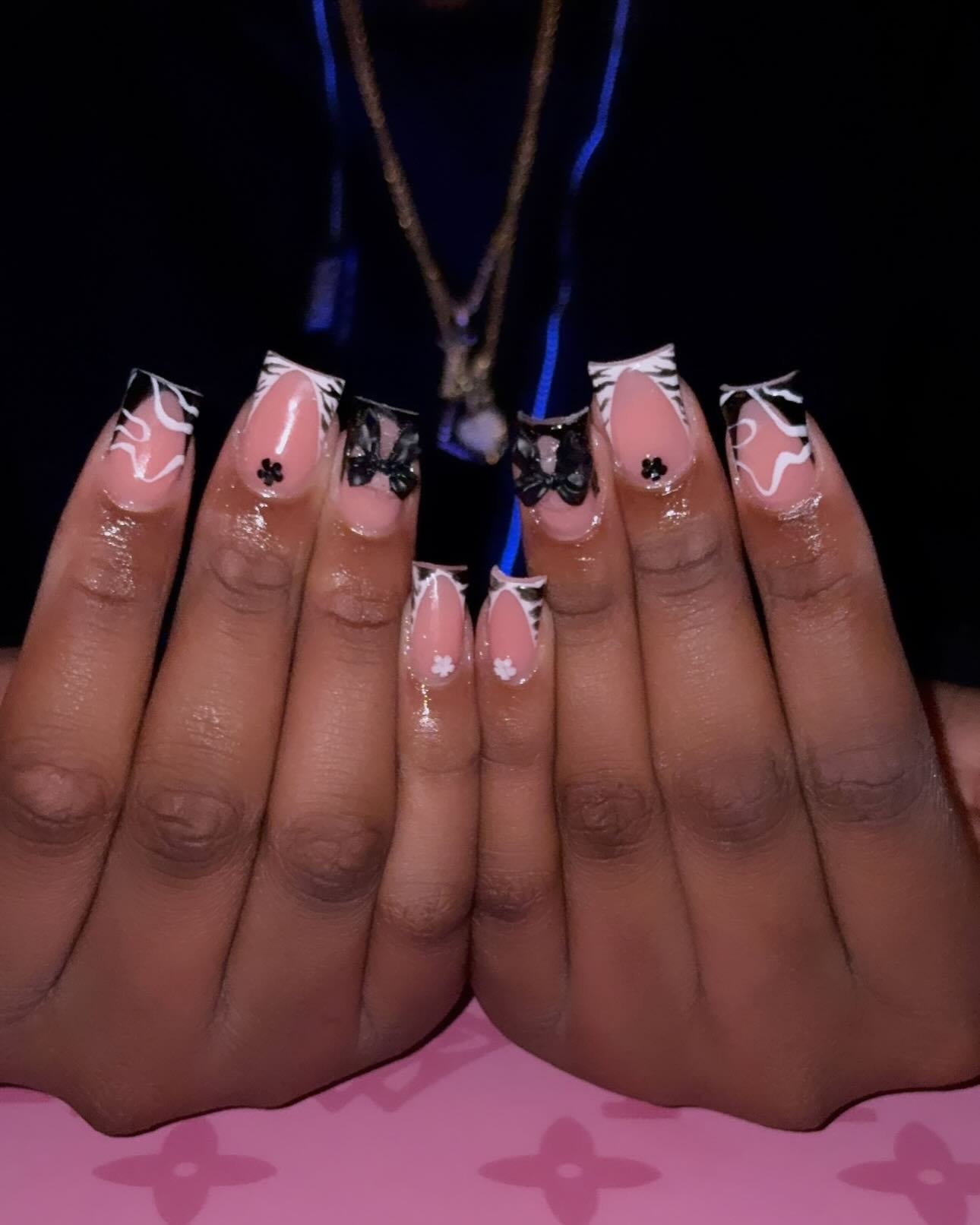 Square set with black French tips, white zebra lines, black bow charms and tiny painted flowers.